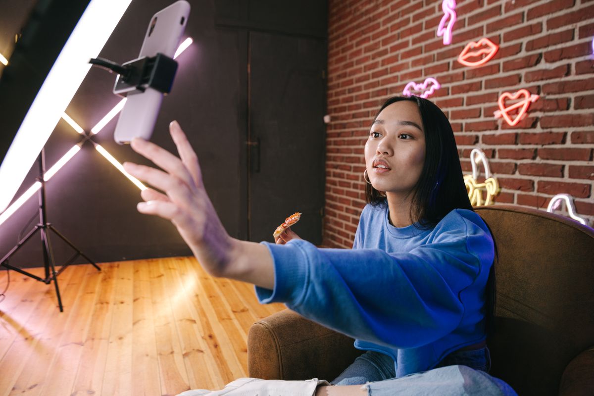 Content creator filming herself on a phone mounted beside a ring light