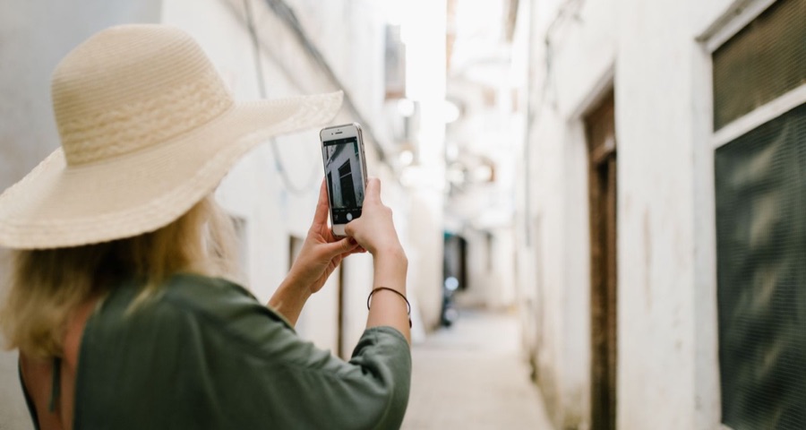Woman taking a photo with her phone in an alley