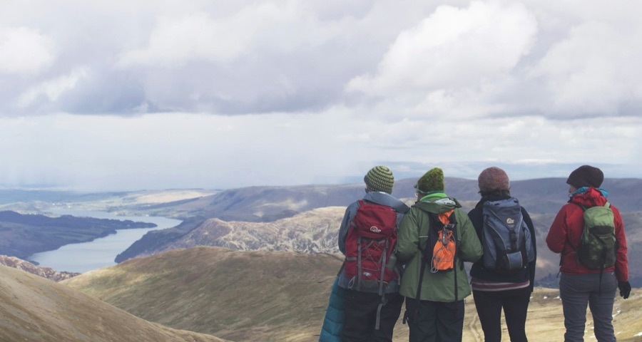 Four friends with backpacks on a hilltop